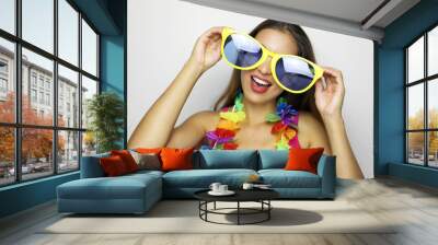 Girl ready for Carnival party. Young woman with big funny sunglasses and carnival garland smile at camera on gray background. Wall mural