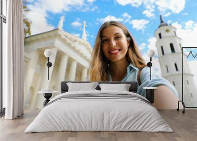 Happy smiling girl taking selfie picture in front of Vilnius Cathedral, Lithuania. Beautiful young woman traveling in Europe. Wall mural