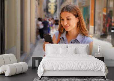 Happy young woman in city street using a mobile phone Wall mural