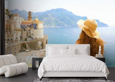 Summer holiday in Italy. Back view of young woman with straw hat and yellow dress with Atrani village on the background, Amalfi Coast, Italy Wall mural