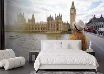 Tourism in London. Back view of traveler girl enjoying sight of Westminster palace and bridge on Thames with famous Big Ben tower in London, UK. Wall mural