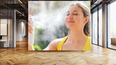 Young woman spraying Thermal Water on her face outside. Thermal water used for skin care, fix makeup, help skin irritation, redness and insect bites. Wall mural