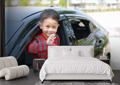 Asian little boy in car smiling and looking camera sitting on a seat of car waving goodbye. Wall mural