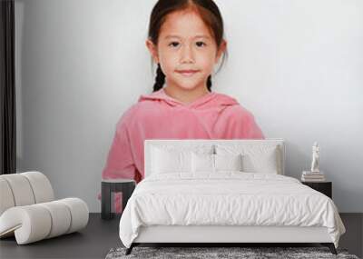 Cute little asian child girl in pink tracksuit with looking at camera practicing mindfulness meditation sitting on white background. Peaceful concept. Wall mural