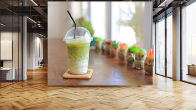 Iced matcha green tea latte with milk with brown straw in take away cup on wooden table at cafe. Wall mural