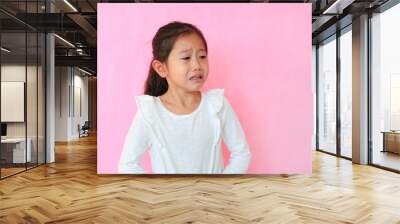 Portrait closeup asian little child girl crying isolated on pink background with copy space. Kid with sad expressions. Wall mural