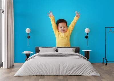 Portrait of happy little asian baby boy expression raise hands up and looking camera isolated over blue background. Wall mural