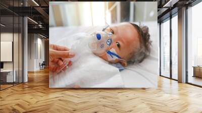 Sick baby boy applying inhale medication by inhalation mask to cure Respiratory Syncytial Virus (RSV) on patient bed at hospital. Wall mural