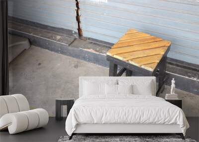 Wooden stool in front of metal door. Wall mural