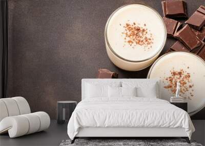 A delicious chocolate smoothie with cacao powder and milk, beautifully served in a glass, showcases fresh ingredients on a dark surface Wall mural