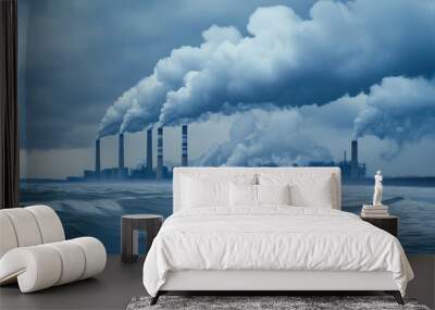 Smoke billows from the chimneys of a power plant near an ocean, with lush land in the foreground and a vibrant blue sky overhead Wall mural