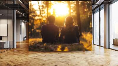 A couple sits together on the forest floor, enjoying the warmth of a vibrant sunset during autumn. The scene evokes feelings of tranquility, connection, and natural beauty. Wall mural