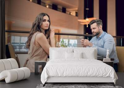 A couple sitting at the table in the restaurant and woman looking unpleased Wall mural