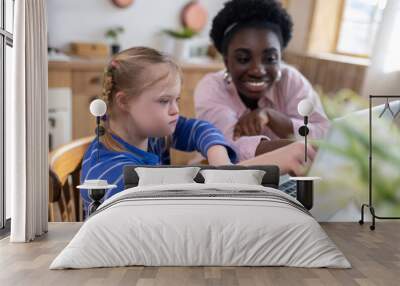 A girl with down syndrome having a lesson with her teacher and looking involved Wall mural