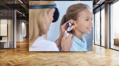 Certified doctor performing an otoscopic exam of the patients ear Wall mural