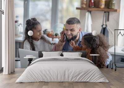 Cheerful curly daughters having fun with daddy Wall mural