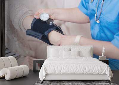 Close up of female doctor checking pressure of elderly patient Wall mural