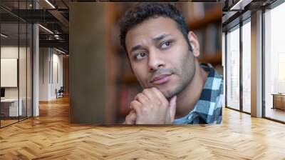 Dark-haired man in a checkered shirt looking serious Wall mural