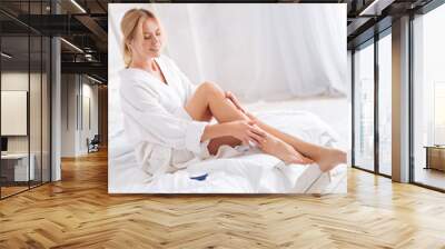 delighted woman massaging her legs Wall mural