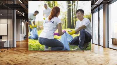 Environmental program. Nice two volunteers carrying garbage bag and looking at each other Wall mural