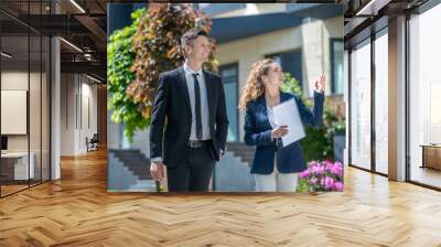 Female broker showing houses with apartments for rent to the client Wall mural