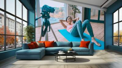 Fitness trainer feeling good while working out abs in front of camera Wall mural