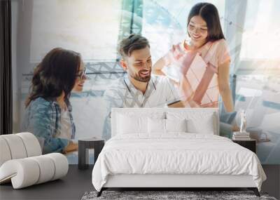 Great team. Happy positive handsome man sitting in front of the laptop and talking to his colleagues while working with them Wall mural