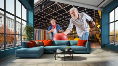 Great throw. Cheerful positive man smiling while throwing the bowling ball Wall mural