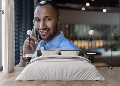 Handsome businessman having smartphone conversation while spending time in cafe during break Wall mural