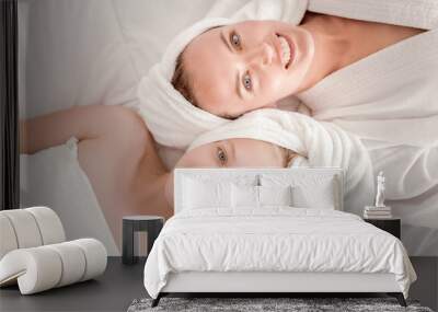 Happy family. Top view of delighted happy mother and daughter looking at you and smiling while lying together Wall mural