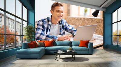 i feel happy. handsome exuberant fair-haired boy working on his laptop and smiling while sitting at  Wall mural