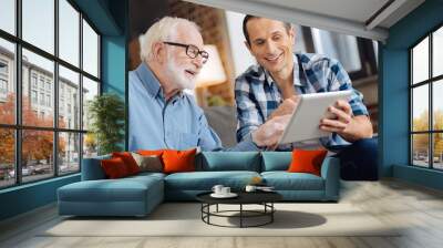 interesting discussion. charming young man and his elderly father reading an article from the table  Wall mural