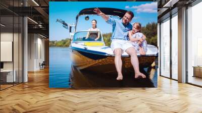 Interesting stories. Cheerful young father pointing at riverbanks and telling his little daughter stories while they sitting on the bow of the boat Wall mural