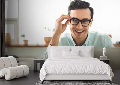 IT professional. Delighted cheerful man touching his glasses while looking at the laptop screen Wall mural