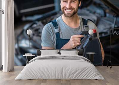 Joyous automotive technician showing the motor oil before the camera Wall mural