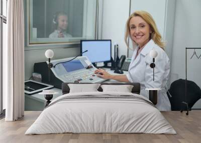 Joyous middle-aged doctor performing an audiometry test Wall mural