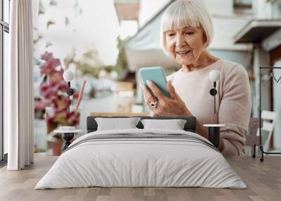 Nice elderly woman looking at her smartphone screen Wall mural