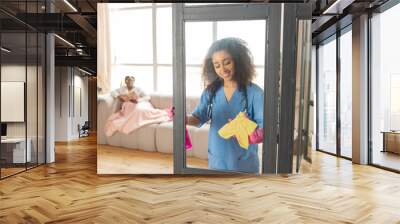 Pleasant nurse talking to patient and cleaning the glass door Wall mural