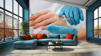 skin rejuvenation. nice skilled beautician holding a female hand while preparing to do an injection  Wall mural