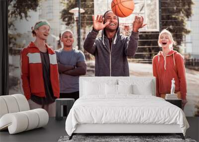 Team leader. Happy joyful man standing in front if his team while throwing up the ball Wall mural