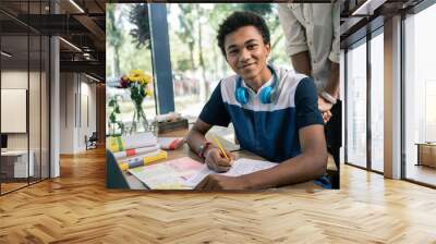 University education. Nice smart student smiling to you while working on his task Wall mural