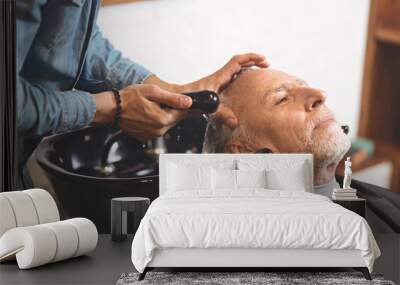 Young barber washing head of the aged client in the barbershop Wall mural