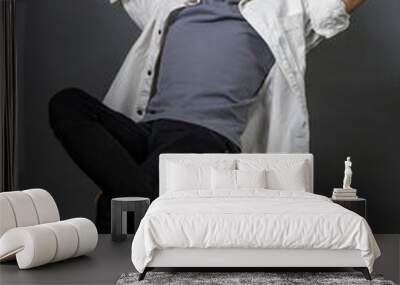 Young curly-haired guy sitting and looking relaxed Wall mural