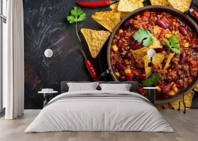 Mexican hot chili con carne in a pan with tortilla chips on a dark background Wall mural