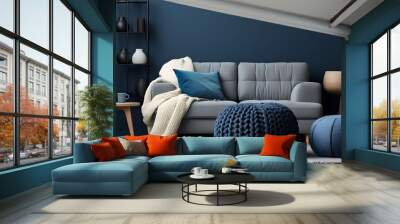 Two knitted poufs near dark blue corner sofa. Scandinavian home interior design of modern living room. Wall mural