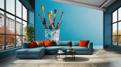 Art brushes in paint in a creative pot on a blue background with space for copy and text. Wall mural