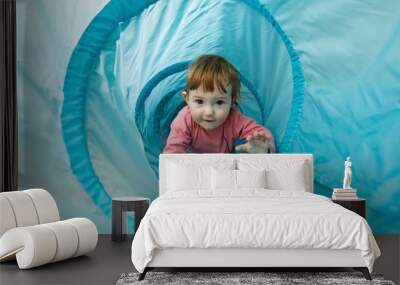 Small toddler playing in a tunnel tube Wall mural