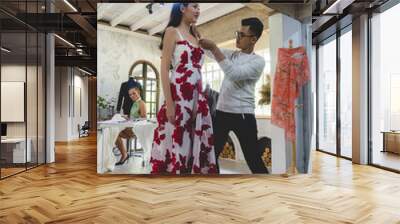 An asian fashion designer is adjusting and fixing a dress on model in the studio Wall mural