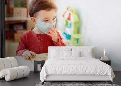 Little boy in medical mask playing letters. He coined the word coronovirus. Wall mural