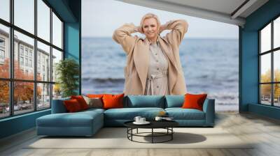 woman aged walking on the beach against the background of the sea Wall mural